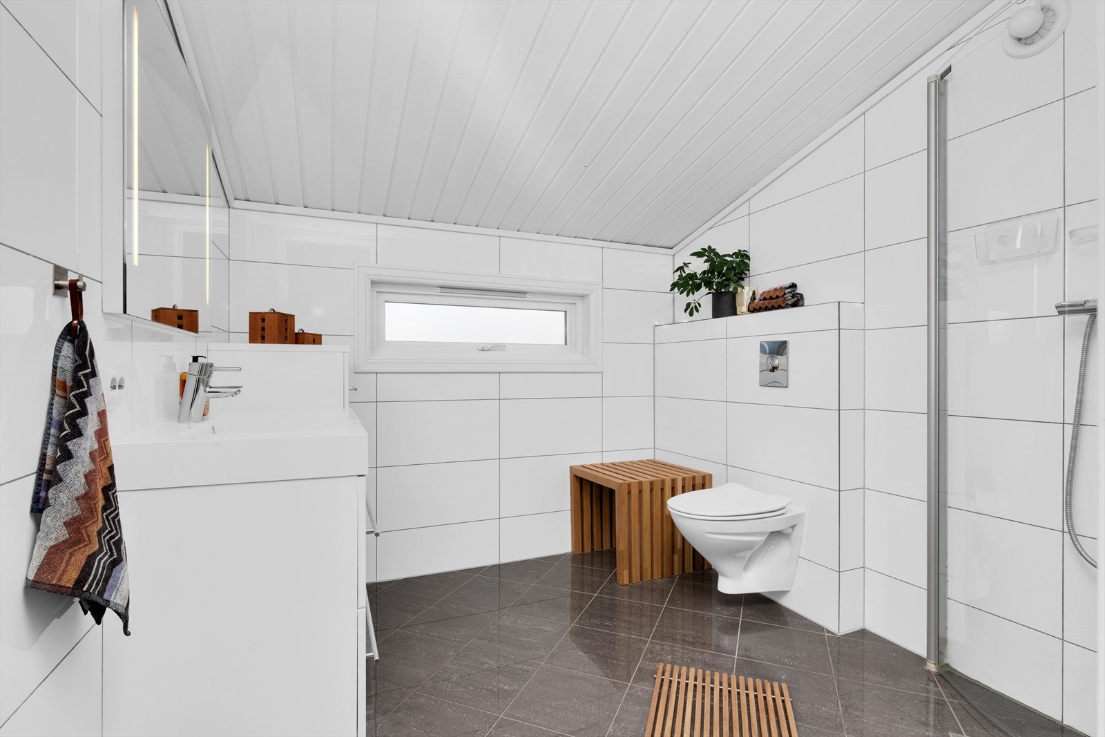 Pent helfliset baderom som ble pusset opp i 2009. Badet er innredet med moderne baderomsinnredning, vegghengt toalett og dusjhjørne Galleribilde