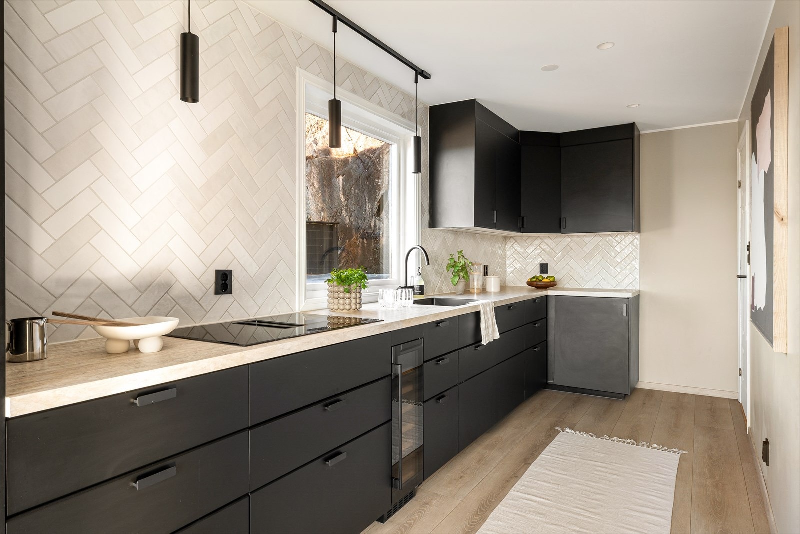 Moderne svart kjøkken med lys benkeplate og lyse fliser- en stilfull kombinasjon av kontrast og lys som gjør rommet innbydende. Galleribilde