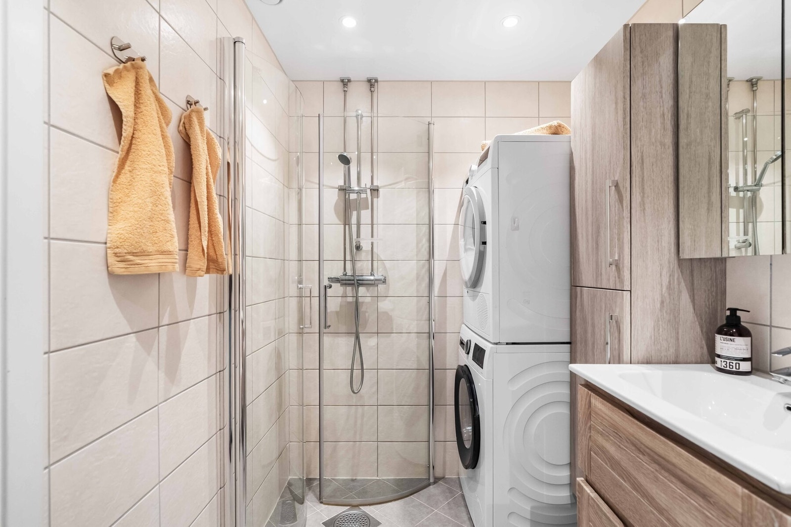 Bad med dusjsone, servantinnredning og opplegg for vaskemaskin. Galleribilde