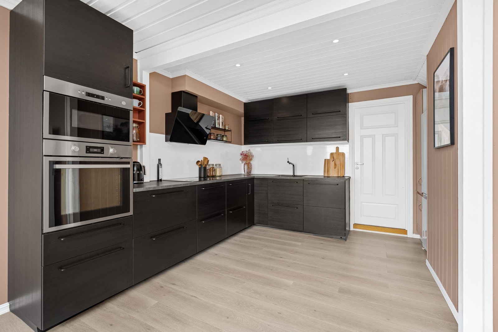 På kjøkkenet er det fine overflater som består av slette vegger, flislagt vegg over benkeplate, laminatgulv og panel i himling. Galleribilde