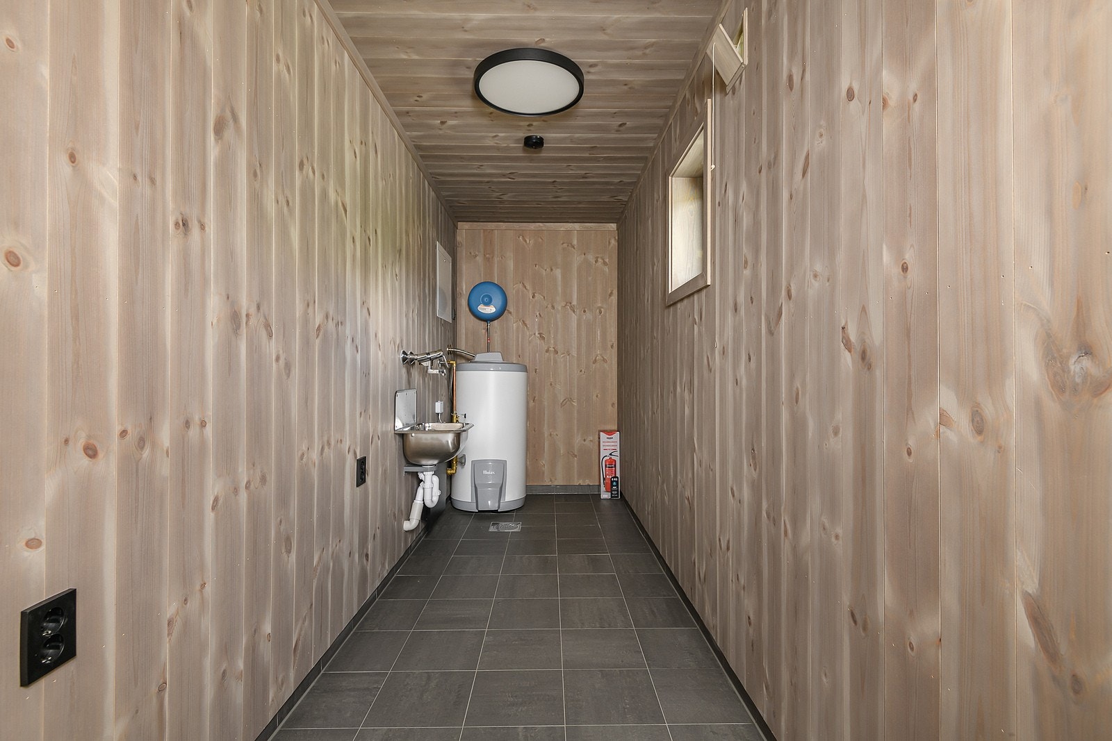 Bod med utvendig adkomst, fliser på gulv med sluk, panel på veggene og i himling. Her finner du bl.a. varmtvannsberederen samt utslagsvask med mulighet for tilkobling av vaskemaskin. Galleribilde