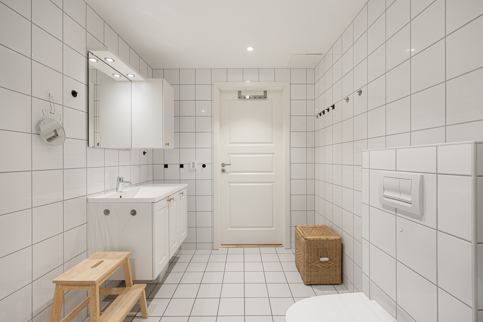 Badet har lyse fliser på gulv og vegger, gulvvarme, downlights og opplegg for vaskemaskin. Galleribilde