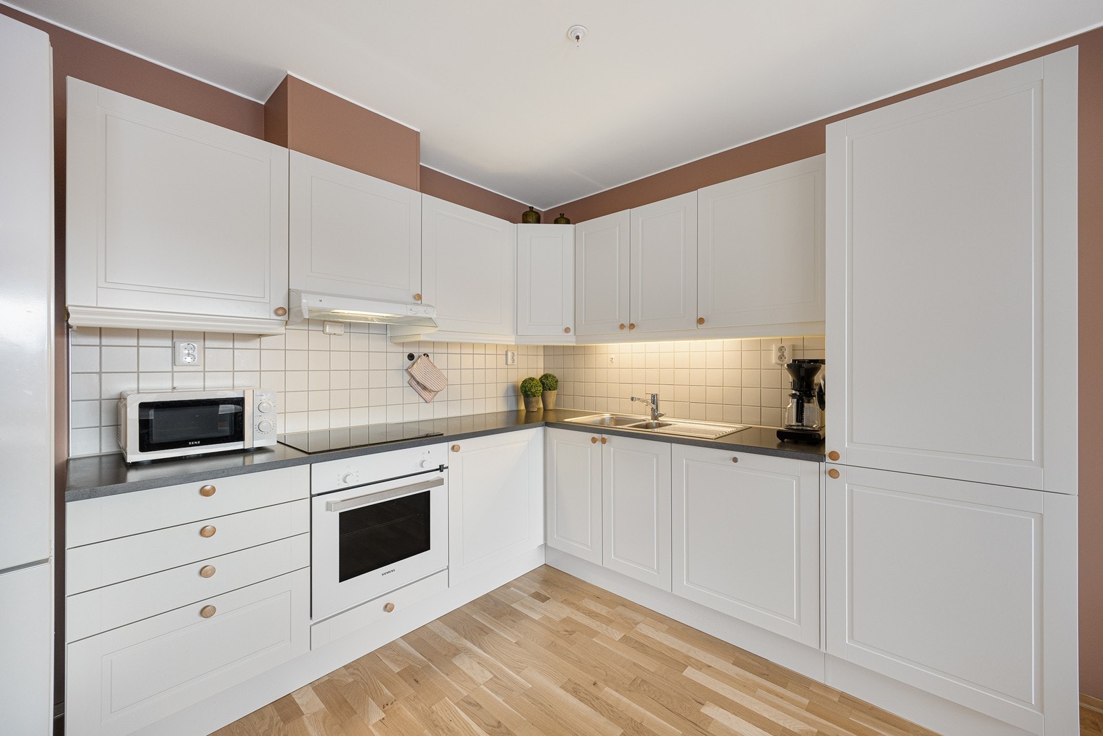 Kjøkkeninnredningen er stilren og moderne med lyse, profilerte fronter, laminert benkeplate og smarte løsninger. Stekeovn, platetopp og oppvaskmaskin er integrert, og rommet har også plass til kjøle/fryseskap. Galleribilde