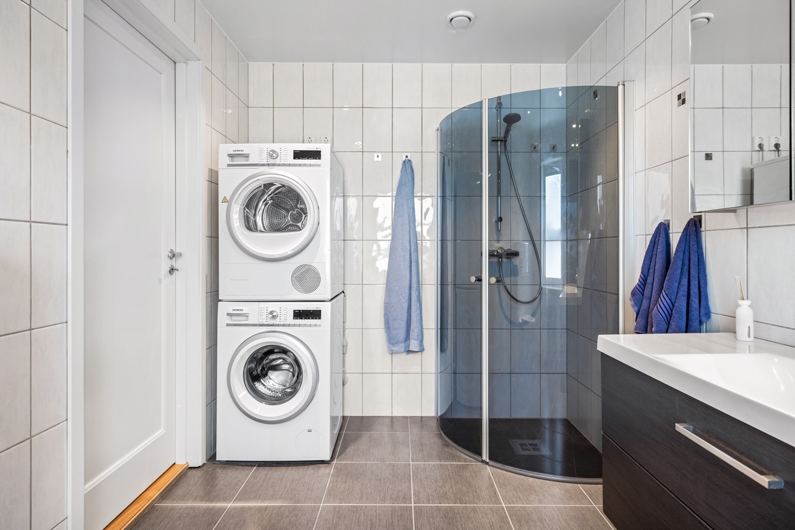 Badet har flislagte overflater, gulvvarme, downlights og opplegg for vaskemaskin. Galleribilde