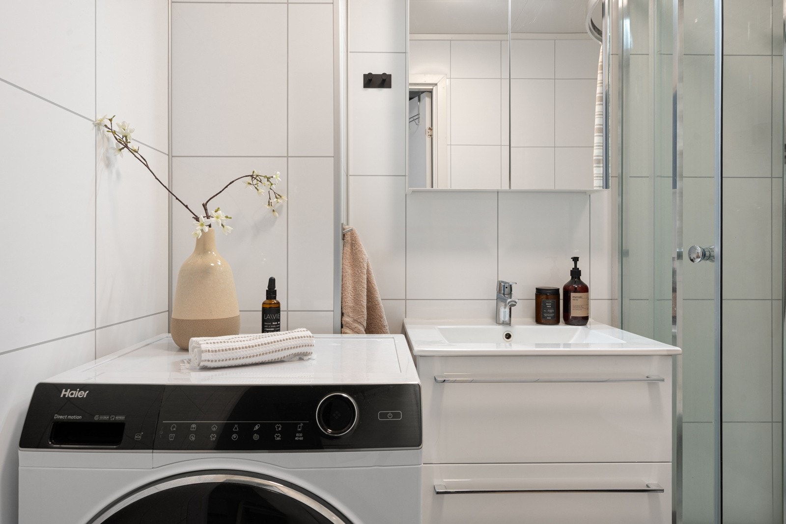 Bad/wc/vaskerom i første plan med fliser på gulv , gulvvarme og opplegg for vaskemaskin Galleribilde