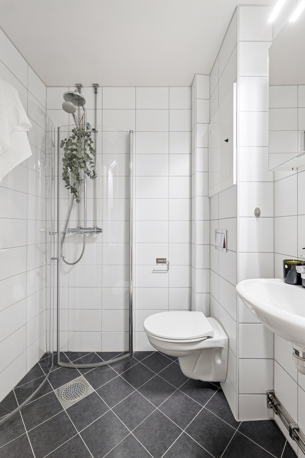 Badet er utstyrt med vegghengt toalett, dusj med innfellbare dusjvegger og speilskap Galleribilde