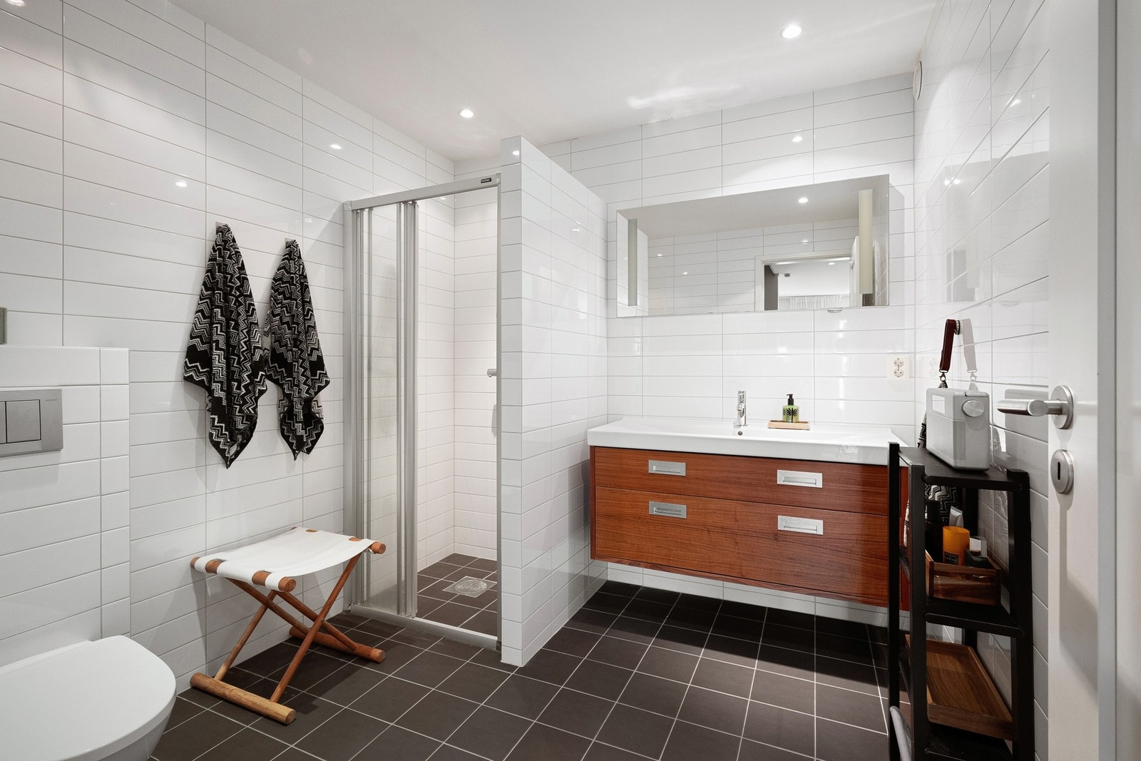 Bad i underetasjen er innredet med skjermet dusjhjørnet med skyvedør, vegghengt toalett, servantinnredning, speil med lys på vegg over servant. Galleribilde