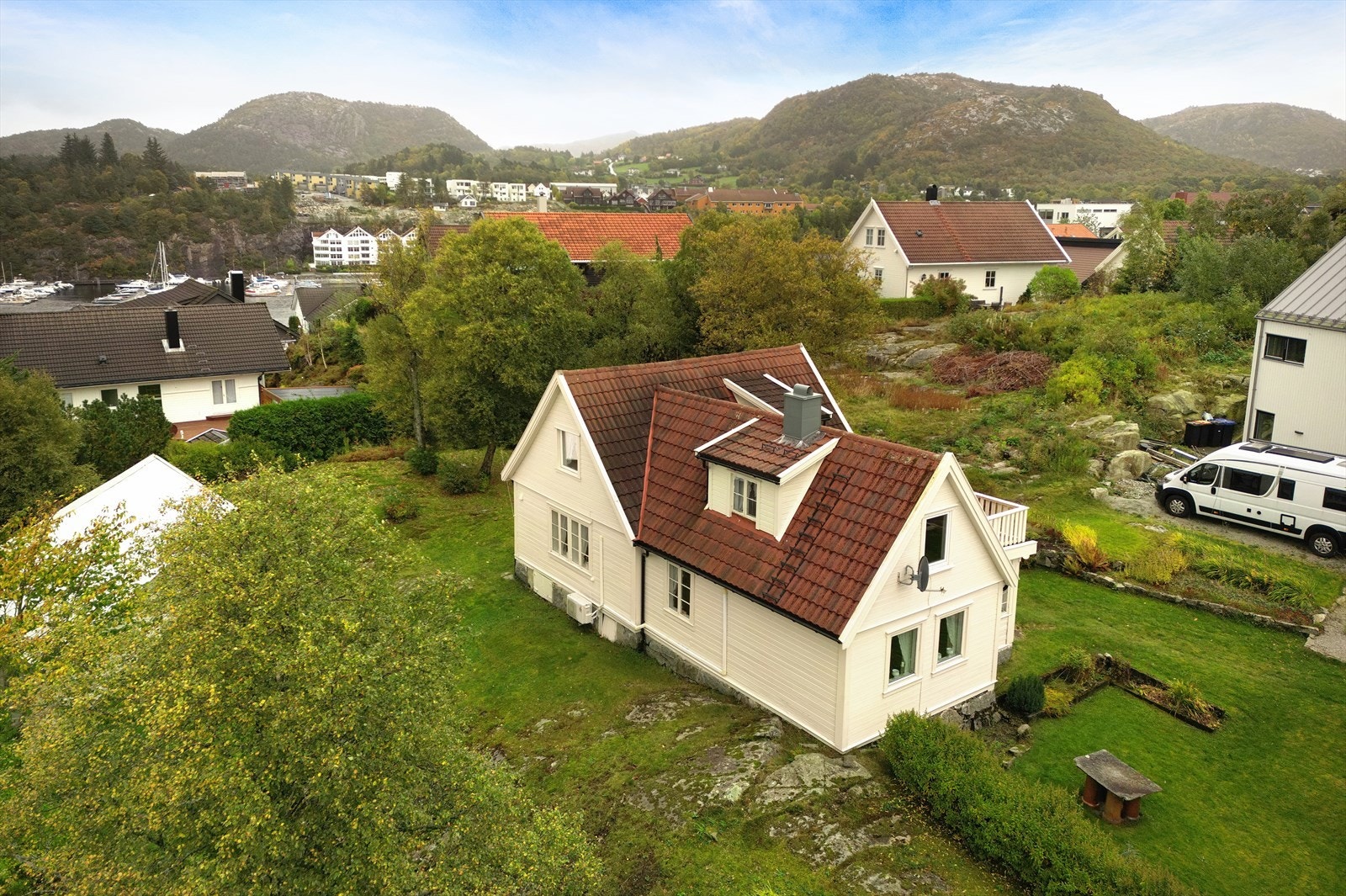 Eneboligen ligger høyt til på en stor tomt, opparbeidet med gressplen, hekk, diverse beplantning og en gruslagt gårdsplass for parkering. Galleribilde