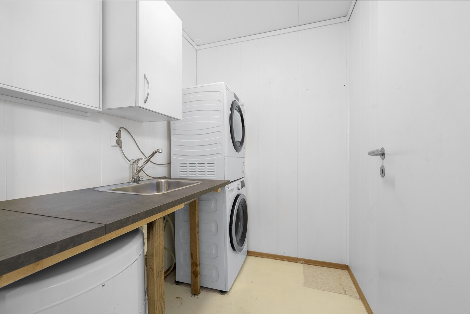 Rommet er innredet med utslagsvask, benkeplate og opplegg for vaskemaskin. Galleribilde