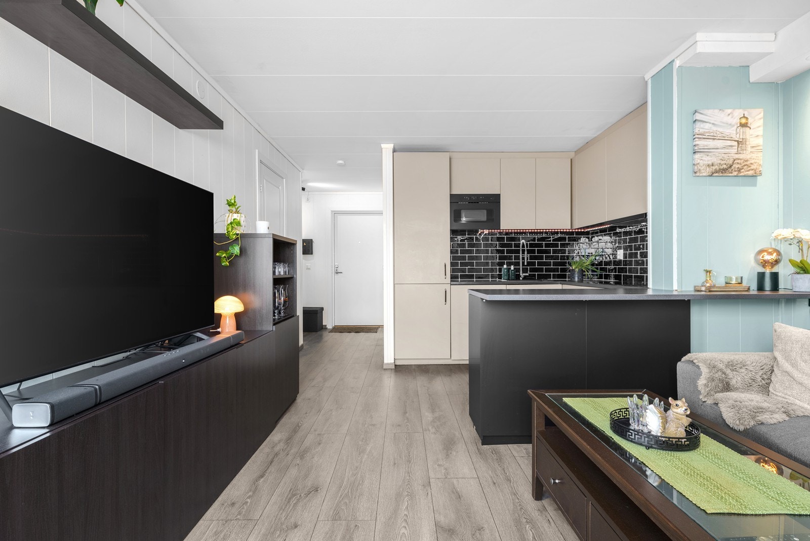 Gjennomgående laminatgulv og malte veggplater gir et helhetlig uttrykk i oppholdsrommene. Galleribilde