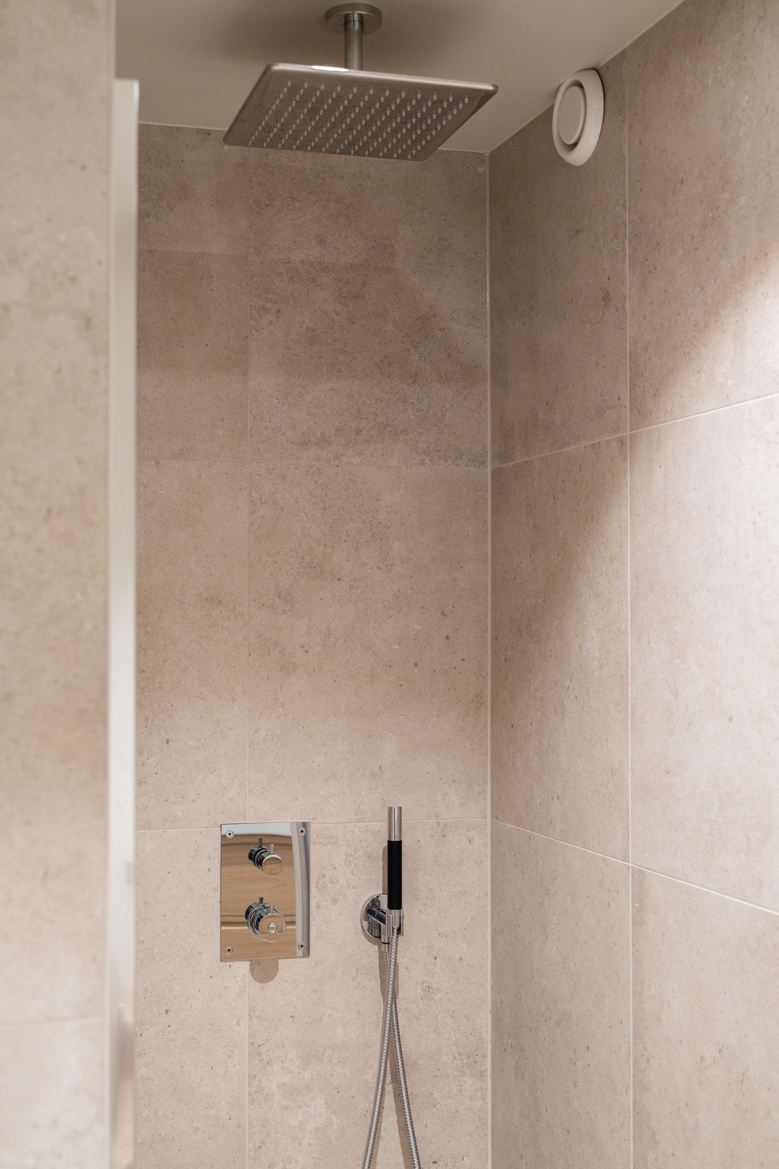 Dusjnisje med glassdør og stilig innebygd armatur med både hånd- og regnfallsdusj. Galleribilde