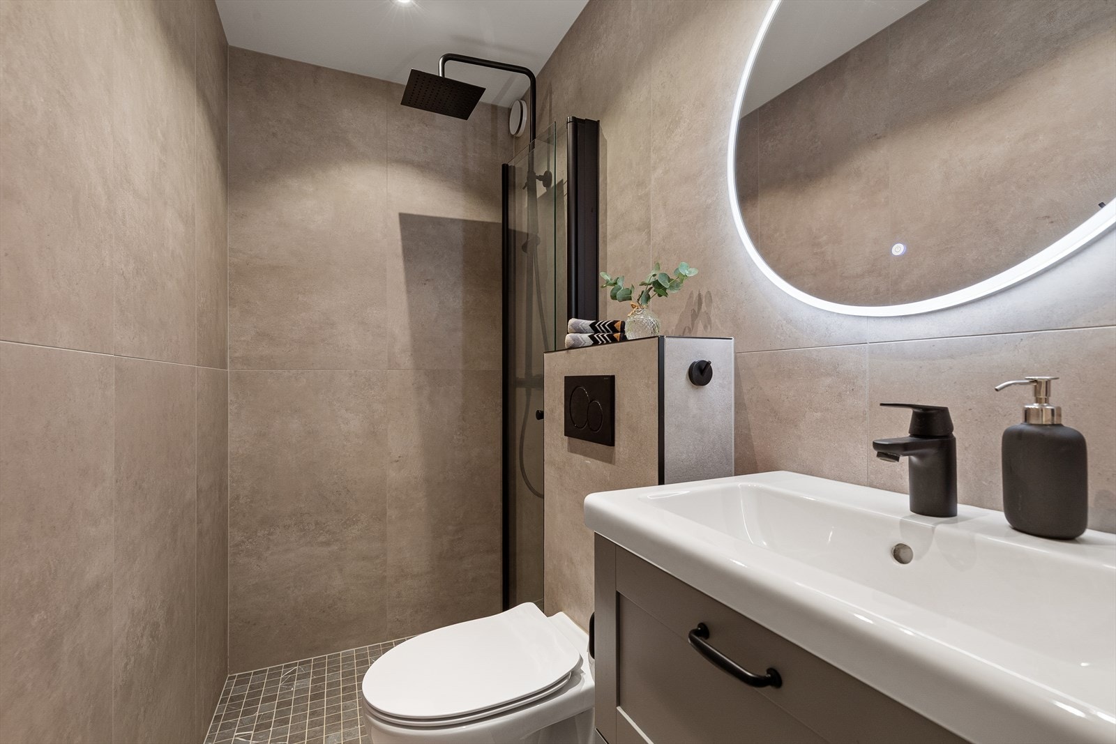 Badet er utstyrt med servant med underskap, dusjhjørne med regndusj og toalett Galleribilde