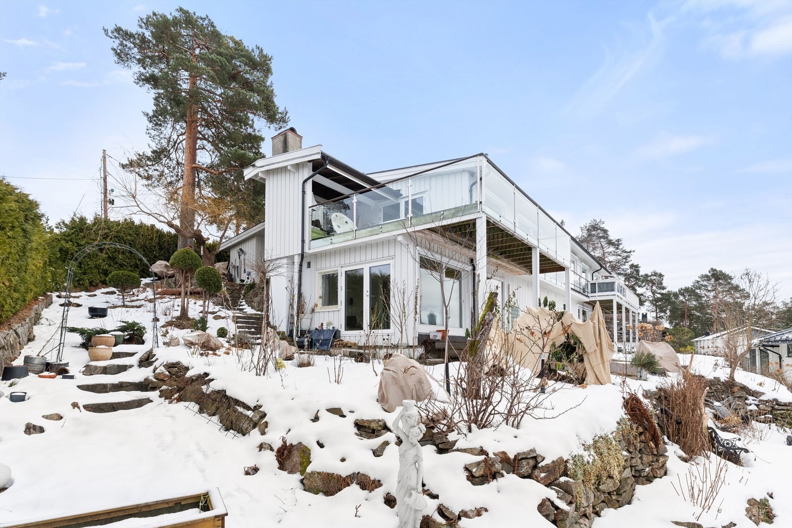 Beplantningen består av velholdt plen, romslige blomsterbed, prydbusker og frukttrær som samlet skaper et variert og tiltalende uteområde. Galleribilde