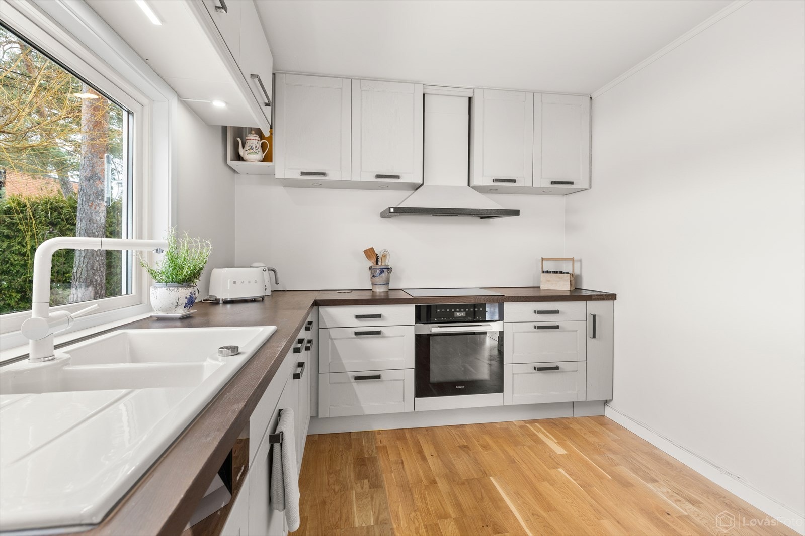 Integrerte hvitevarer fra Miele samt nedfelt servant i hvit utførelse. Rikelig med skap- og benkeplass, samt plass til en mindre spisegruppe. Galleribilde