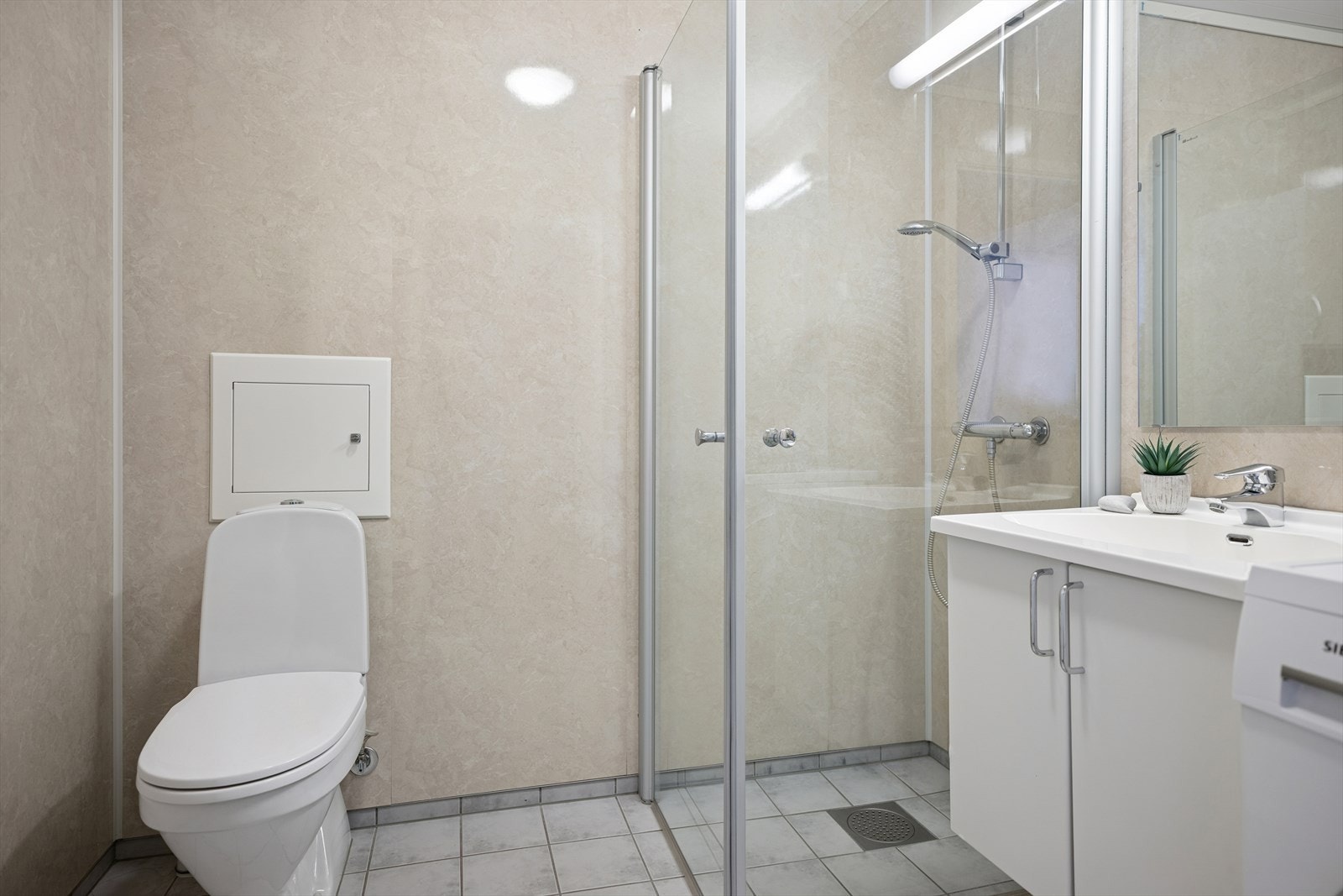 Rommet er utstyrt med dusj med glassdører, toalett og servant med skap. Galleribilde