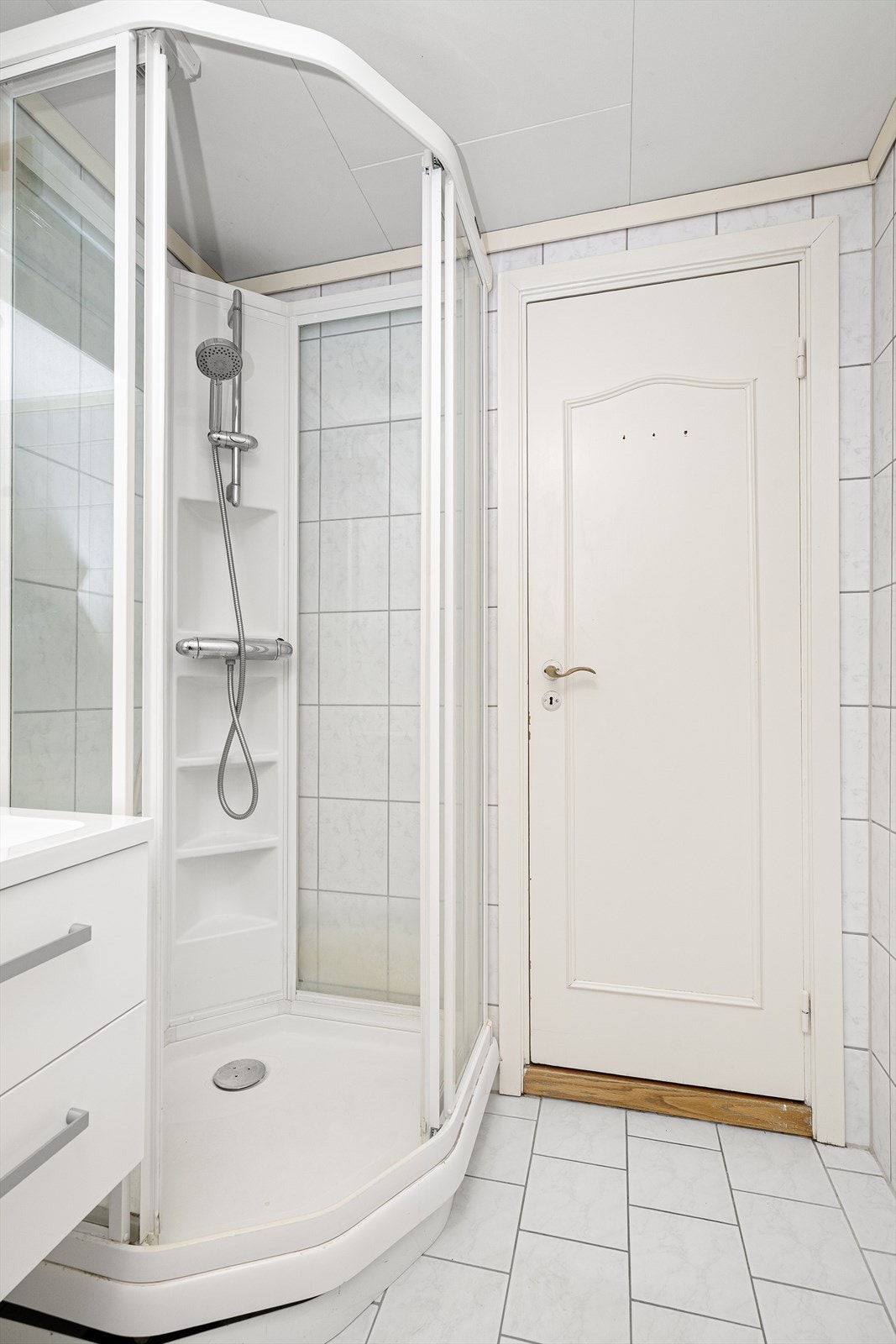 Her er en moderne innredning med dype skuffer og heldekkende servant, samt speil med overlys. Badet er også innredet med dusjkabinett, toalett og opplegg for vaskemaskin. Galleribilde