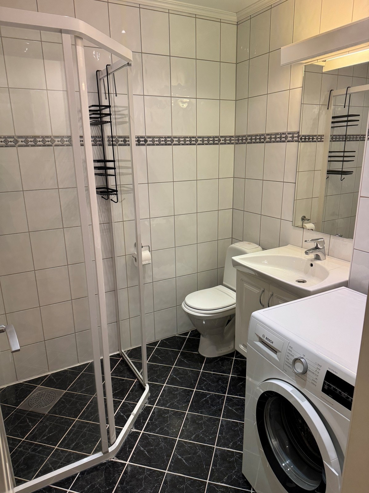 Badet er helfliset og inneholder dusj, toalett, servant og vaskemaskin. Galleribilde