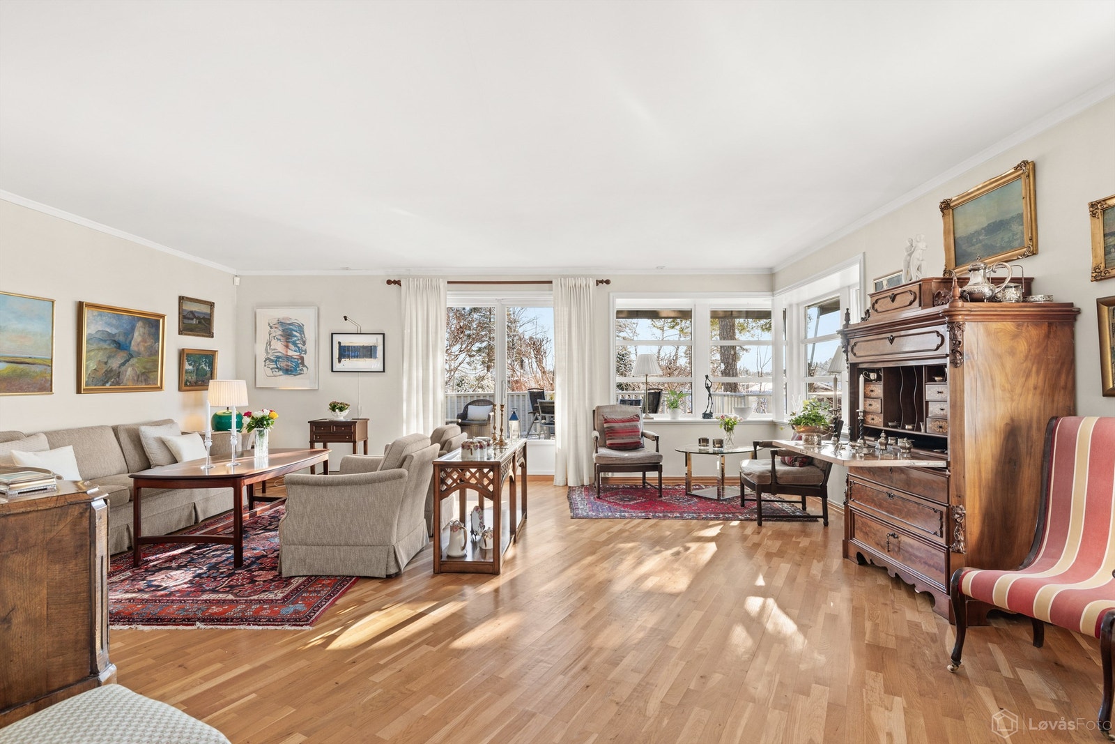 Stuen er romslig med parkett på gulvet og store vindusflater som gir rikelig med dagslys Galleribilde