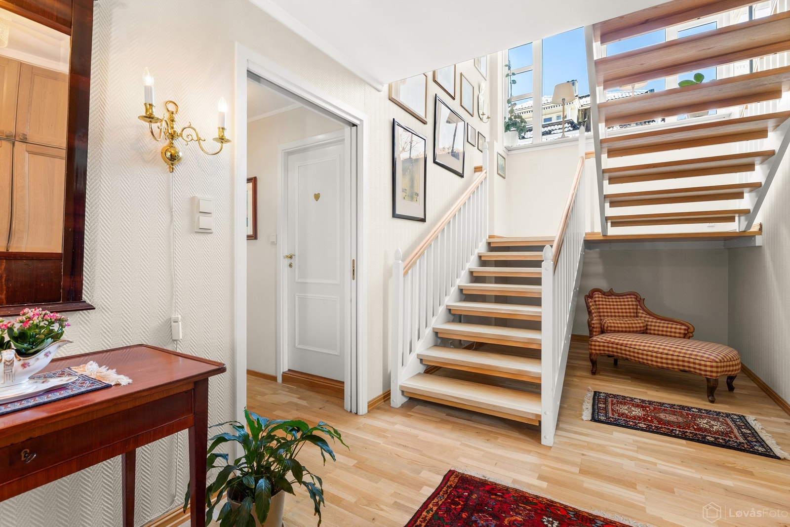 Romslig hall med garderobeskap. Store vindusflater i trappeløpet gir hallen godt med naturlig lys Galleribilde