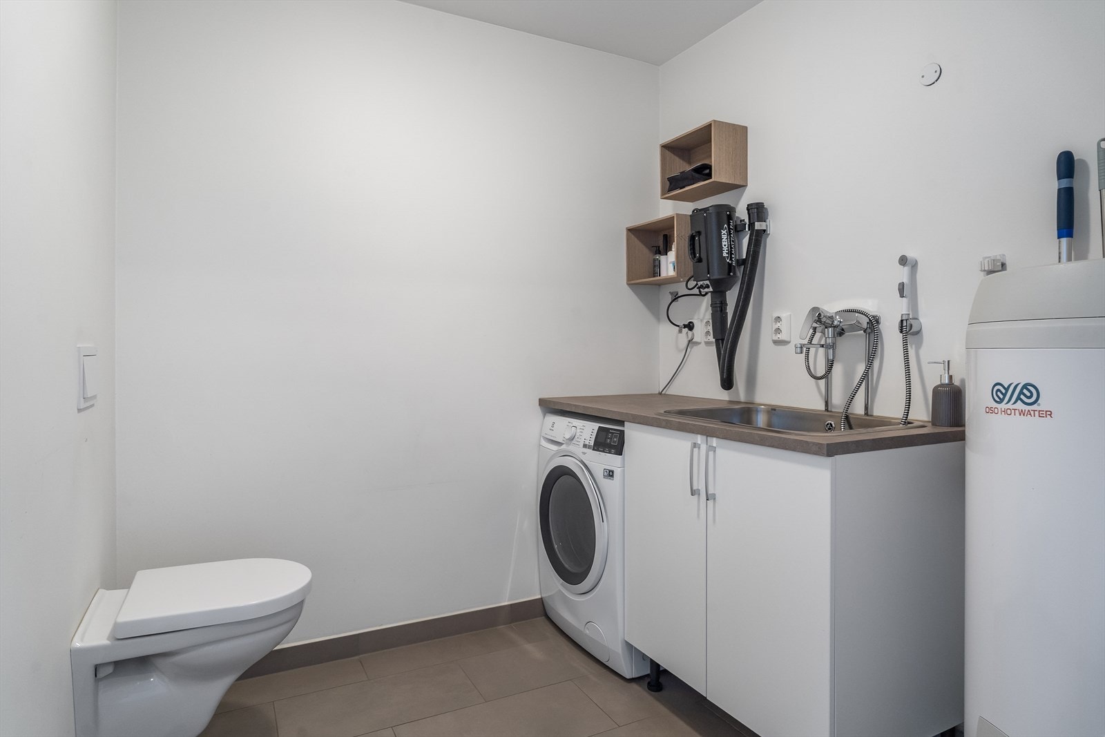 Eget vaskerom med opplegg for vaskemaskin og tørketrommel. Rommet har også toalett, praktisk for hverdagsbruk og som ekstra gjestetoalett. Galleribilde