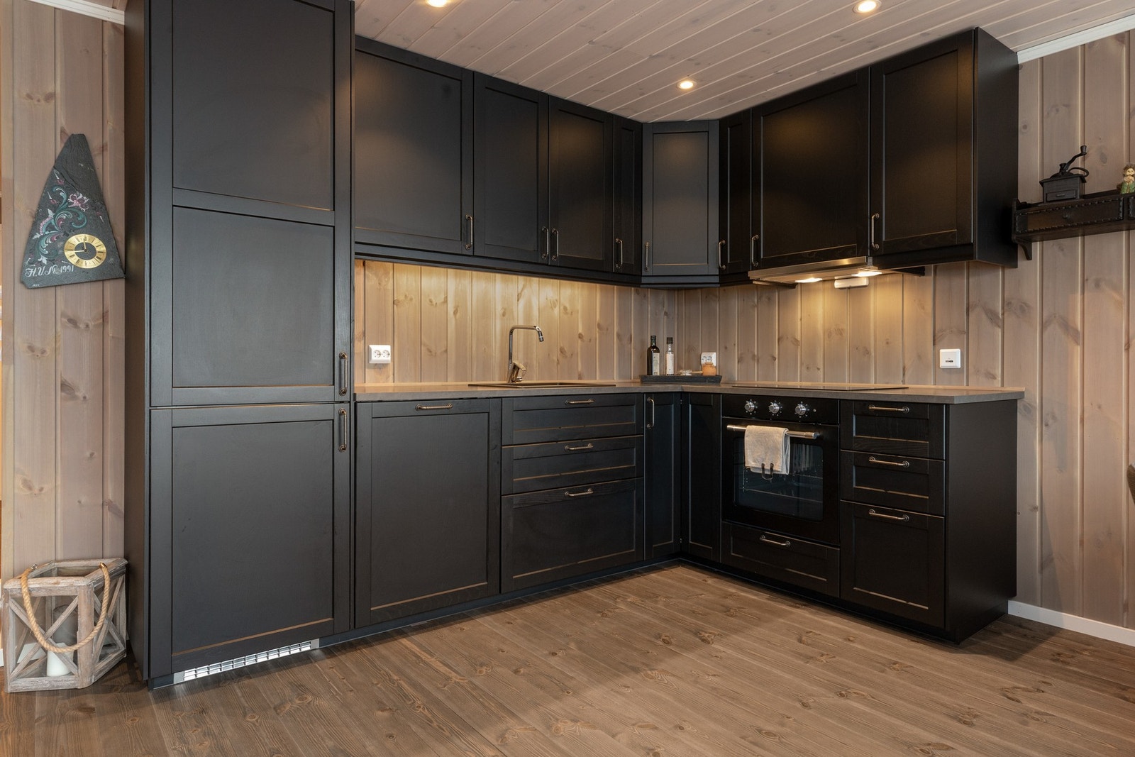 Kjøkkeninnredningen er i dempet sort, overskap går til himling Galleribilde