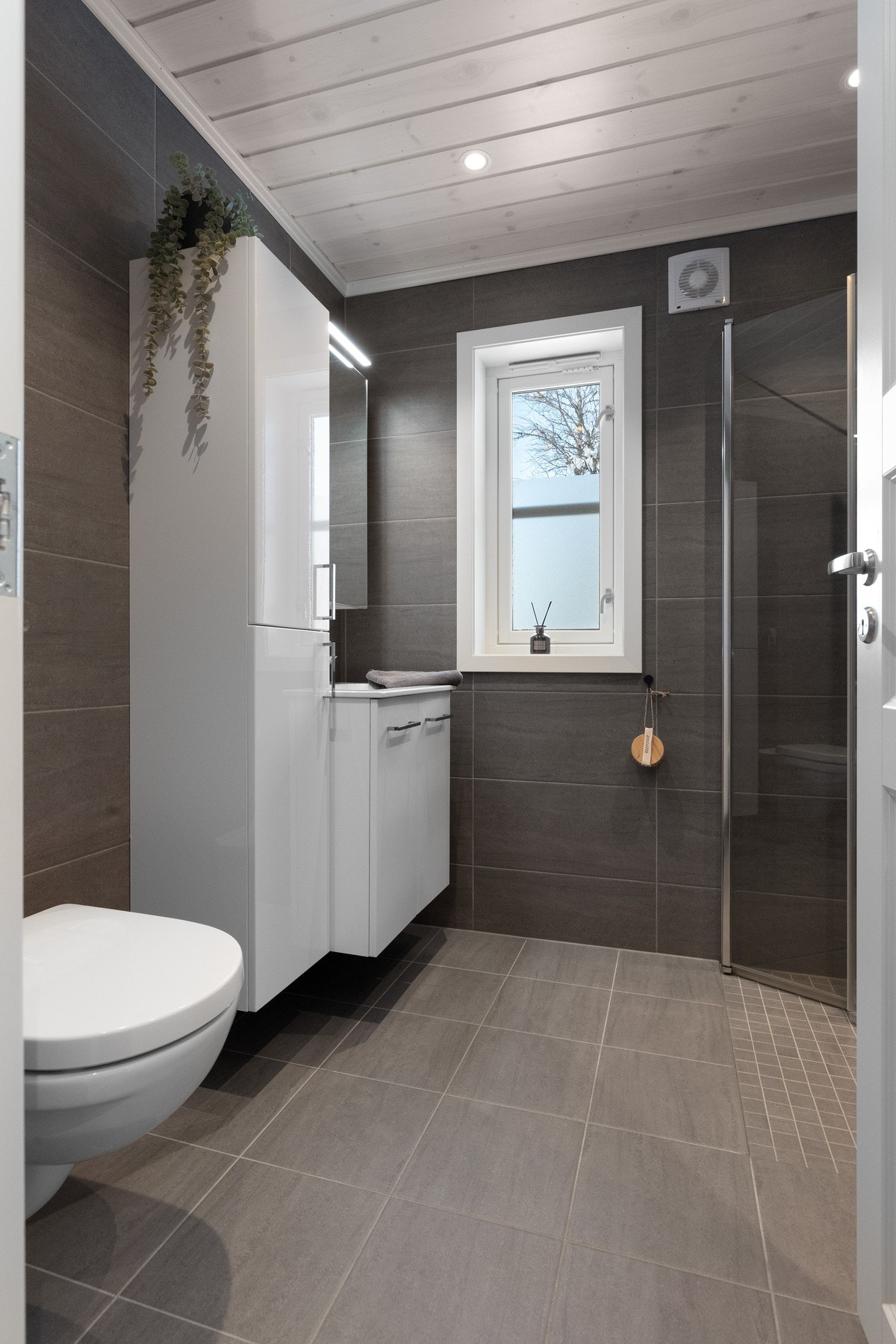 Badet er utført med grå rektangulære fliser på vegg Galleribilde