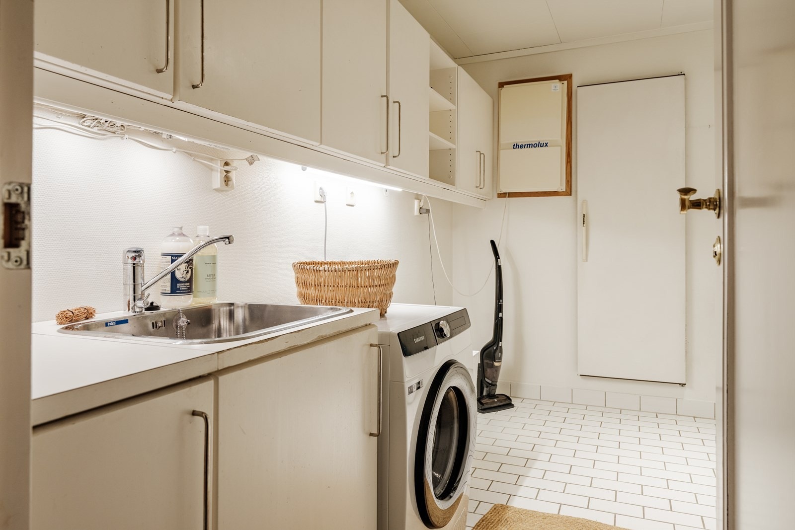 I 1. etasje er det i tillegg vaskerom med opplegg for vaskemaskin og tørketrommel, varmtvannsbereder, vannmåler og stoppekran. I tilknytning til vaskerommet er det etablert kjølerom med støpt gulv, panel på vegger og i himling, samt kjøleenhet. Galleribilde