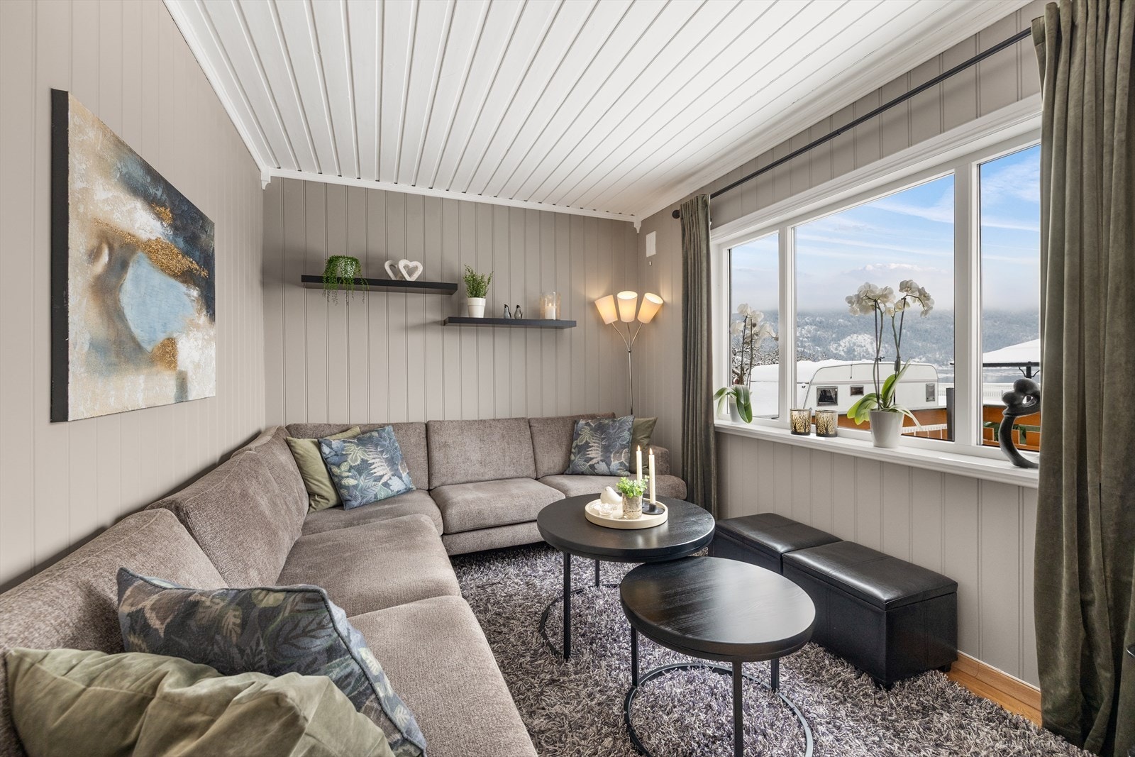 Koselig og innbydende stue med parkett på gulv og panel vegger malt i en pen fargetone, som gir rommet en lun følelse. Galleribilde