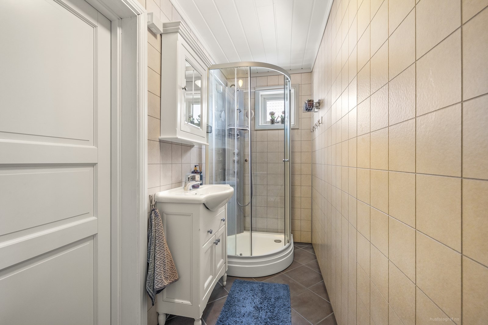 Eldre flislagt gulv på baderom 1.etasje med servantinnredning med speil, toalett og dusjkabinett. Galleribilde