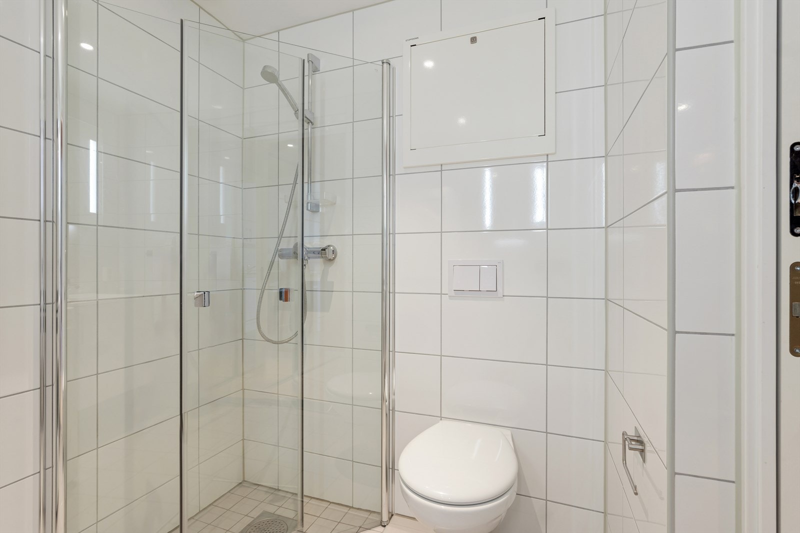 Baderommet er innredet med innfellbare dusjvegger, vegghengt toalett og servant med skap. Galleribilde