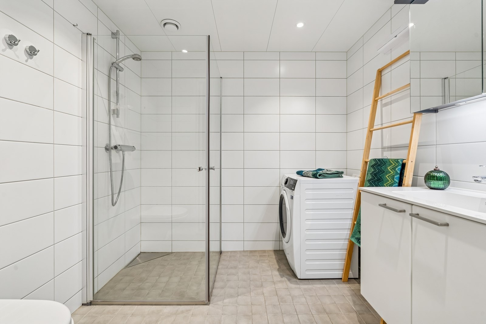 Lyst og stilrent baderom med fliser på vegger og gulv. Opplev for vaskemaskin. Galleribilde