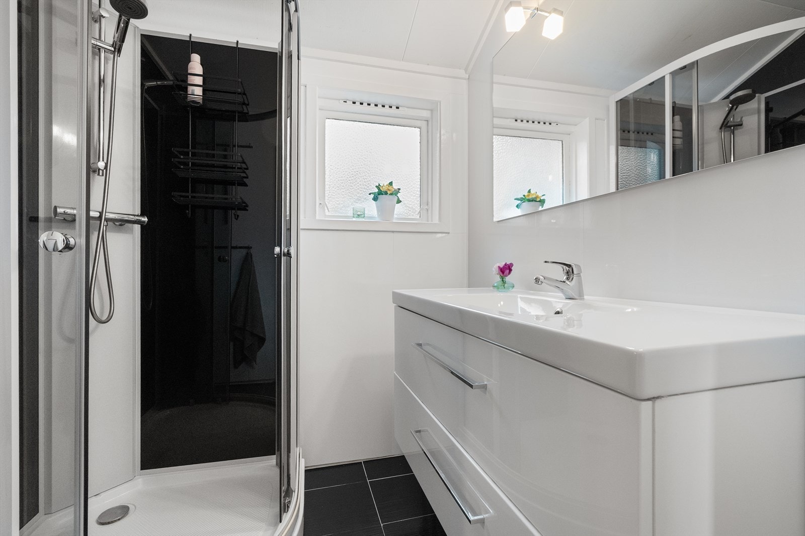 Badet er innredet med dusjkabinett, skuffeinnredning med servant og toalett, og har varmekabler i gulv Galleribilde