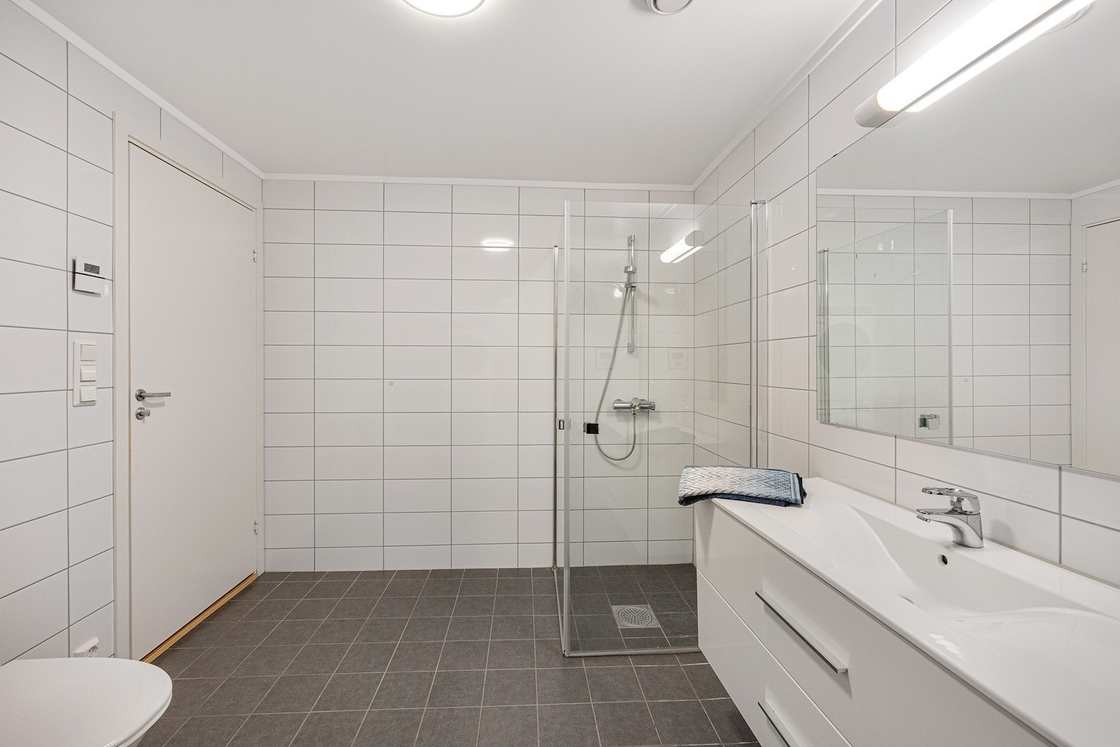 Videre har badet gulvmontert toalett og dusjhjørne med innfellbare vegger i herdet glass. Galleribilde