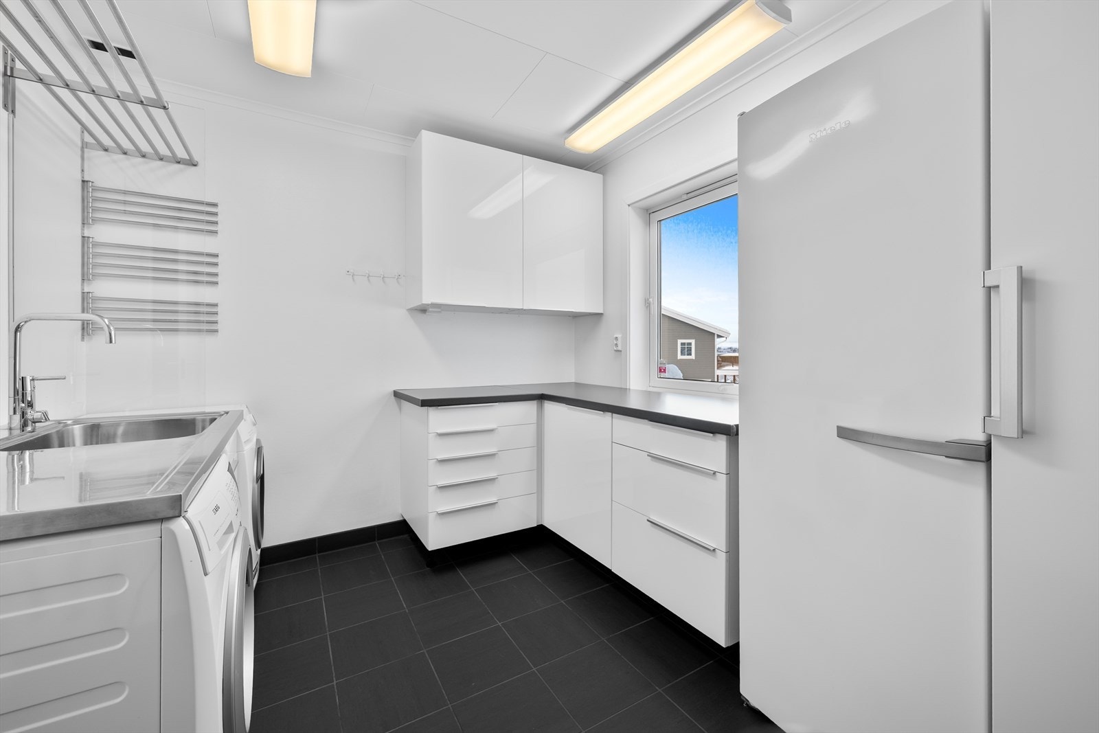 Praktisk vaskerom med mye skap - og benkeplass. Det er varmekabler i gulv. Galleribilde