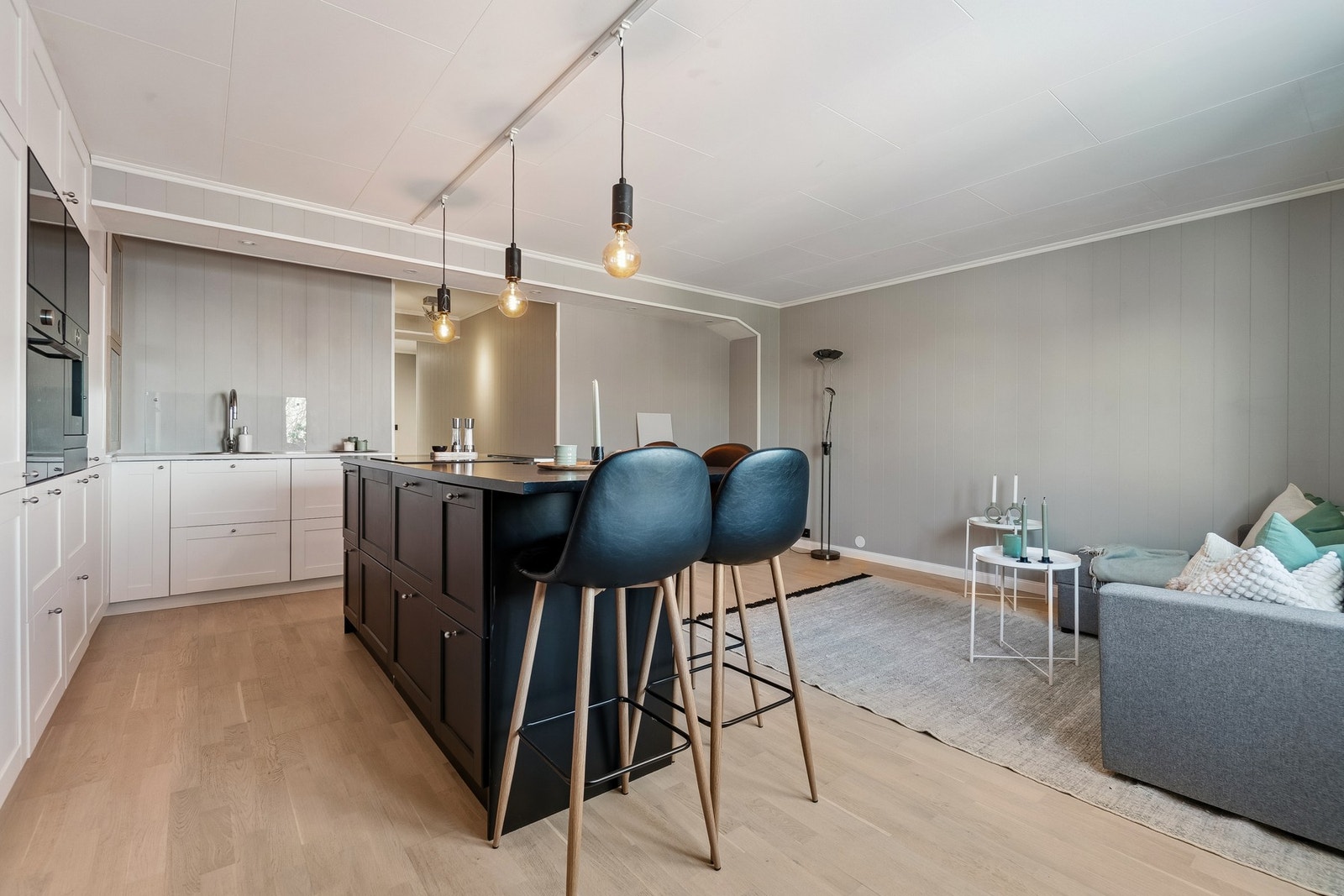 Boligens stue ligger i en åpen planløsning med kjøkkenet, og rommet er utformet i en rektangulær form. Galleribilde