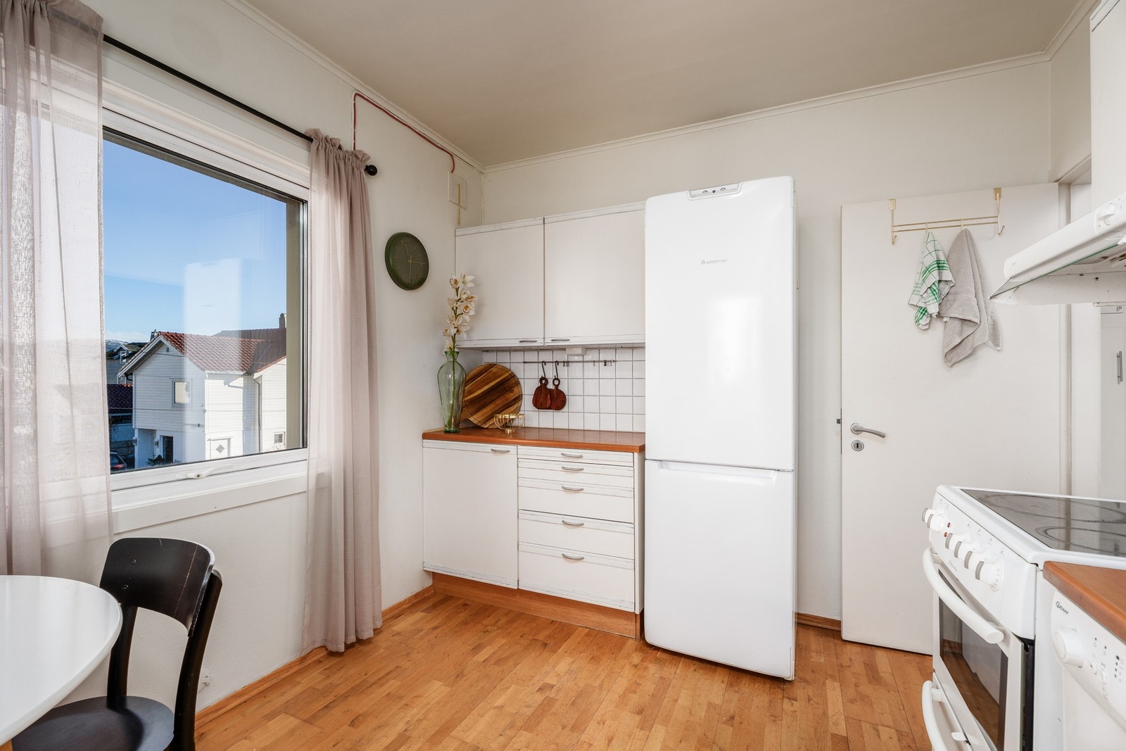 Kjøkkeninnredning med hvite glatte fronter. Laminat benkeplate. Av hvitevarer er her oppvaskmaskin, komfyr og kjøleskap. Ventilator med avtrekk ut Galleribilde