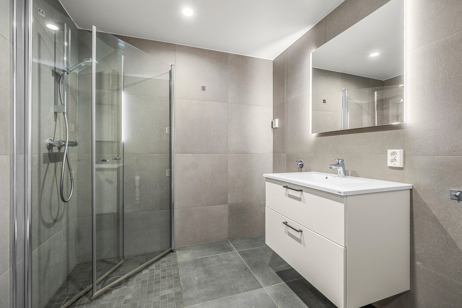 Badet er utstyrt med servant med skuffer, vegghengt wc, dusjhjørne og opplegg for vaskemaskin Galleribilde