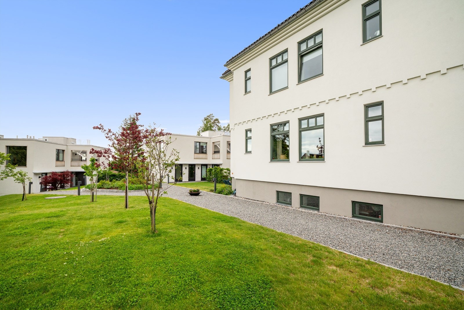 Utvendig er fellesarealene pent opparbeidet med gressplen, beplantning, naturstein og belysning Galleribilde