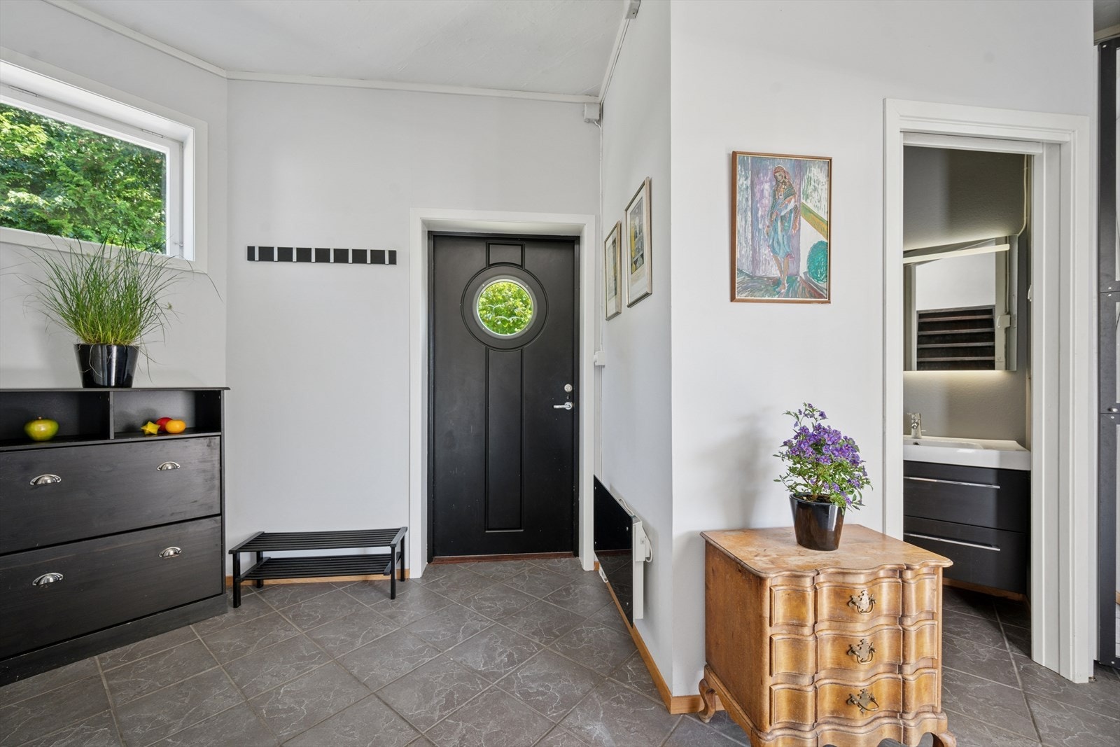 Innenfor døren møtes du av en romslig og praktisk entré med lyse, glatte vegger og grå fliser med behagelig gulvvarme. Galleribilde