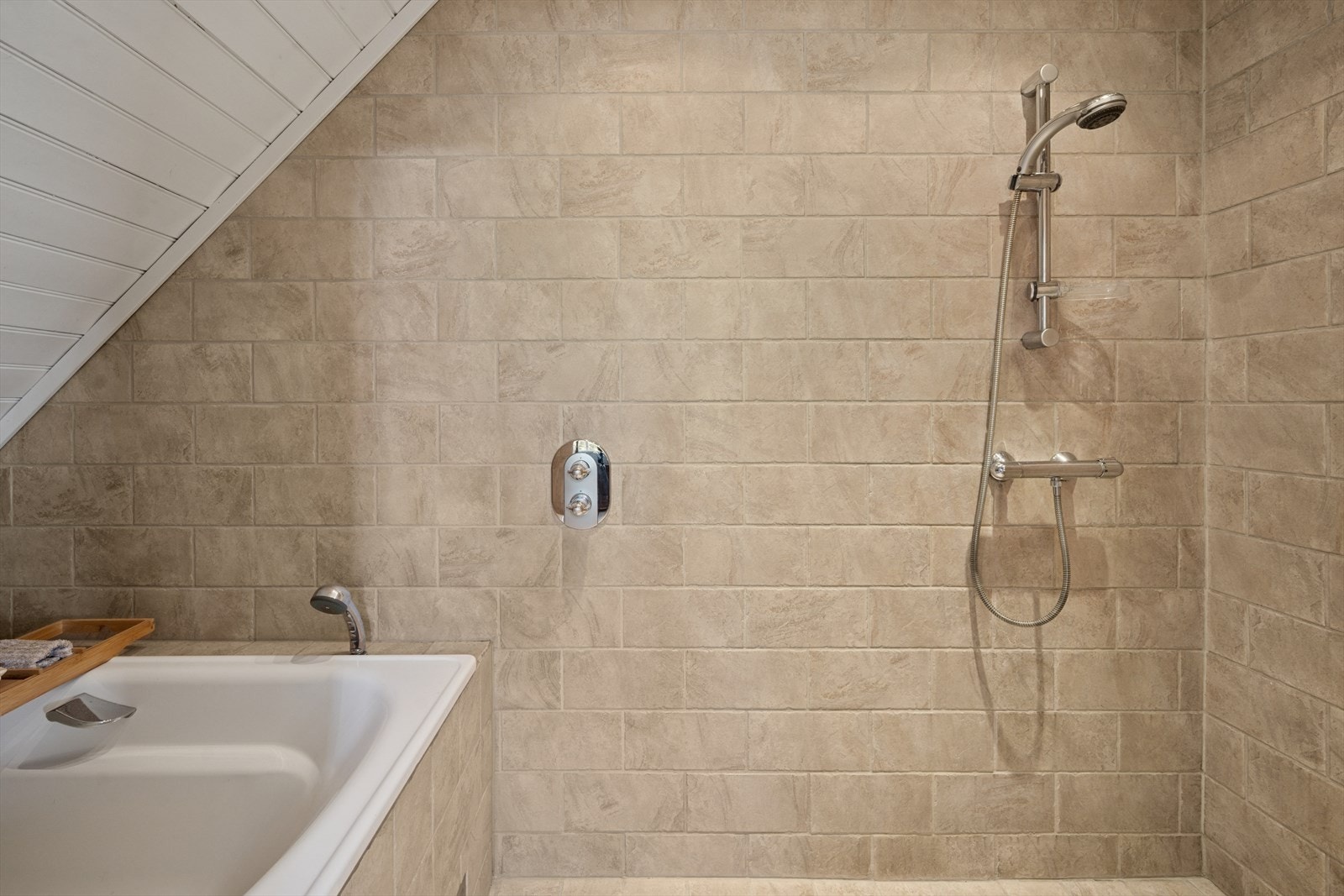 Dusjsonen er plassert i et eget rom, og består av vegghengt dusjsett og et innfliset badekar. Galleribilde