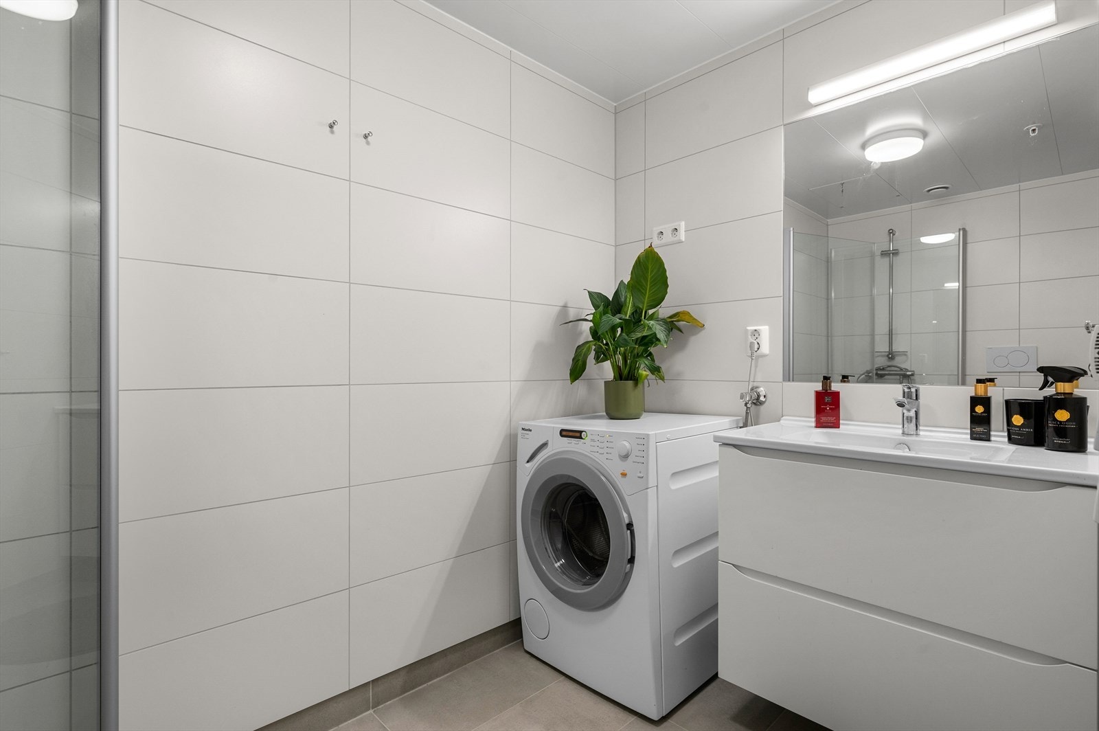 Baderommet fremstår lyst og tidløst med flislagte vegger og gulv. Galleribilde