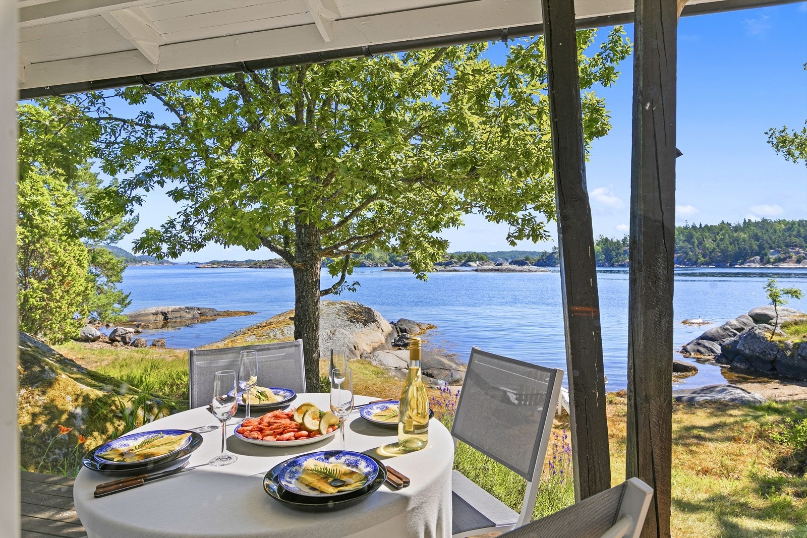 Ved strandhytta, på den overbygde terrassen med utsikt mot Rytterholmane. Galleribilde