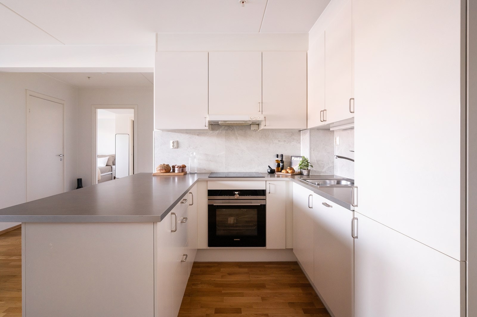 Moderne kjøkken fra HTH med lyse, glatte fronter og laminat benkeplate med nedfelt vaskekum. Det er rikelig med både skap- og benkeplass. Galleribilde