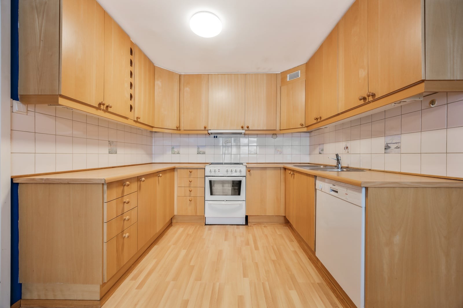 Kjøkkenet har en eldre innredning i eikefiner med glatte fronter og laminat benkeplate. Galleribilde