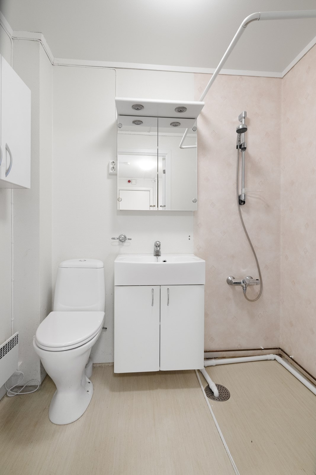 Badet inneholder heldekkende servant med underskap, speilskap med lys over, veggmontert skap, gulvmontert toalett, dusjnisje og opplegg til vaskemaskin Galleribilde