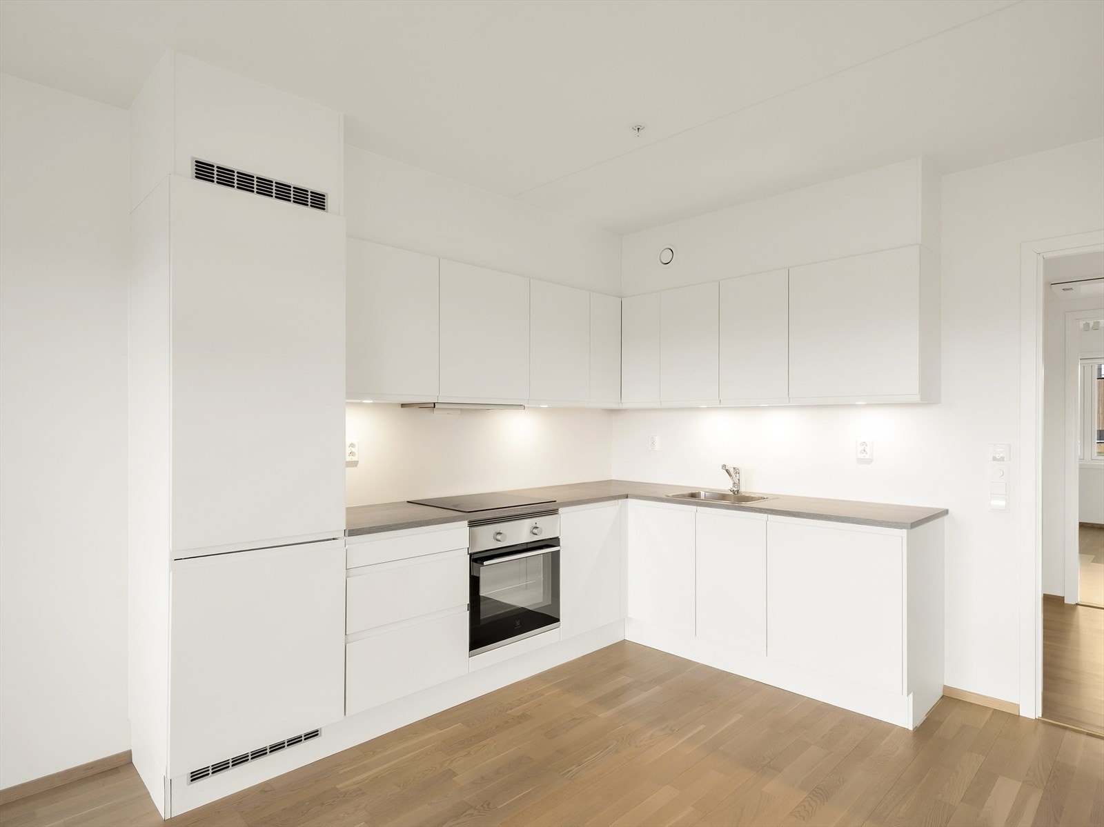 Stilrent HTH-kjøkken med slette, lyse fronter og fullt integrerte hvitevarer. Galleribilde