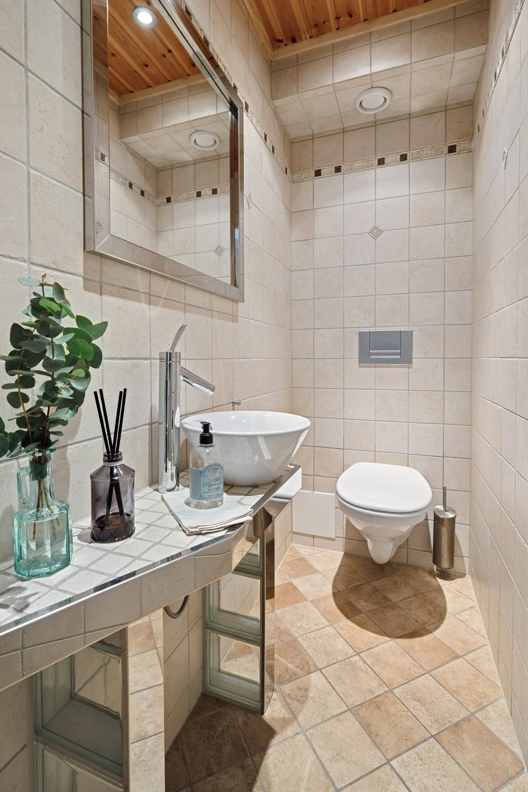 Toalettrom med vegghengt toalett, servant og fliser på gulv / vegg. Galleribilde