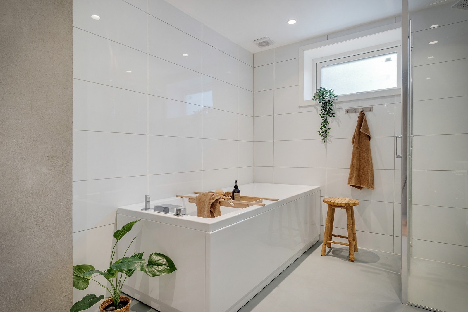 Innredet med vegghengt toalett, dusjnisje med glassdør, badekar, servant med møblement, speil og belysning. Galleribilde