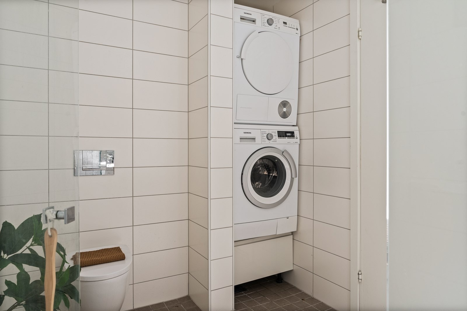 Badet er utstyrt med nedfelt servant, veggmontert toalett, dusjvegger og opplegg for vaskemaskin. Galleribilde