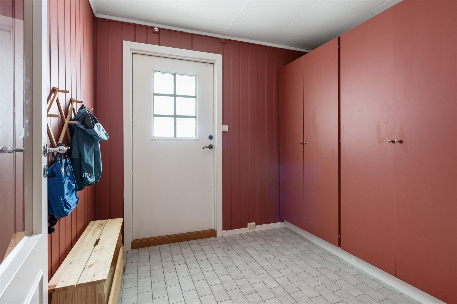 Stor entre med flislagt gulv og garderobeløsning. Galleribilde